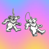 Silver bear-shaped earrings on a colorful gradient background